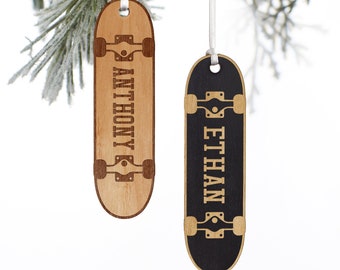 May include: Two wooden skateboard-shaped ornaments hanging from white ribbons. One is light brown with the name "ANTHONY" engraved, the other is black with "ETHAN" engraved. Both have brown wheels and trucks.