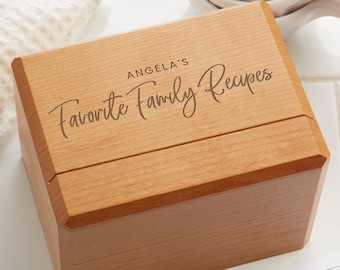 May include: A wooden recipe box with a sliding lid. The lid is engraved with the text "Angela's Favorite Family Recipes".