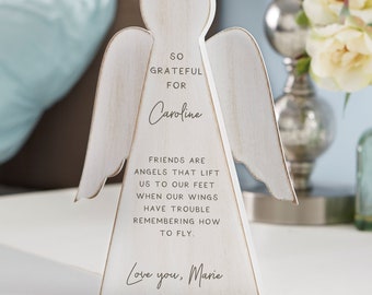 May include: White wooden angel figurine with the text "So grateful for Caroline. Friends are angels that lift us to our feet when our wings have trouble remembering how to fly. Love you, Marie."