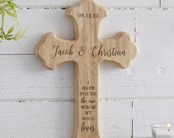 May include: A wooden cross with the text "Jacob & Christina" and the date "09.15.23" engraved on the top. The cross also features the text "I have found the one whom my soul loves" and "Song of Solomon 3:4".