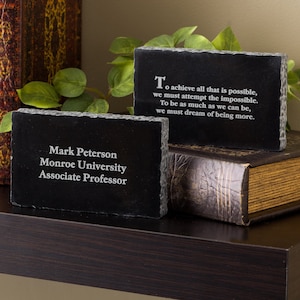 May include: Two black slate plaques with white text. The top plaque has a quote about achieving the impossible. The bottom plaque reads "Mark Peterson, Monroe University, Associate Professor".