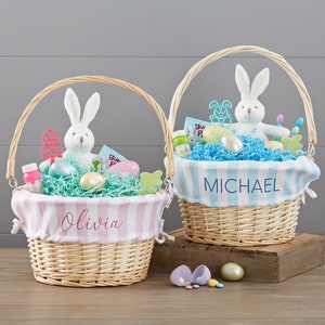 May include: Two wicker Easter baskets with handles, each filled with Easter treats. One basket has a pink and white striped liner with the name "Olivia", and the other has a blue and white striped liner with the name "Michael". Both baskets contain a plush bunny.