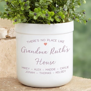 May include: White ceramic planter with the text "THERE'S NO PLACE LIKE Grandma Ruth's House" and a pink heart. The names Mikey, Alex, Maddie, Caylie, Jonah, Thomas, and Kelsey are listed below the text.