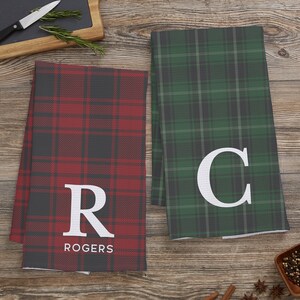 May include: Two kitchen towels with plaid patterns. One is red and black with the letter "R" and the name "ROGERS" printed on it. The other is green and black with the letter "C" printed on it.