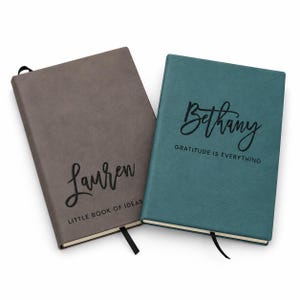 May include: Two rectangular notebooks with ribbon bookmarks. The gray notebook features the black text "Lauren" and "LITTLE BOOK OF IDEAS". The teal notebook features the black text "Bethany" and "GRATITUDE IS EVERYTHING" in a script and sans-serif font.