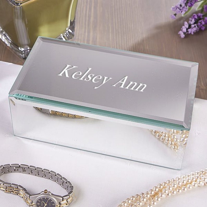 May include: A clear glass mirrored jewelry box with a hinged lid. The lid is engraved with the name "Kelsey Ann".
