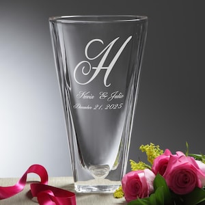 May include: A clear glass vase with a unique, angular design. The vase is engraved with the letter "A", the names "Kevin & Julie", and the date "December 21, 2025". Pink roses and a red ribbon are in the foreground.