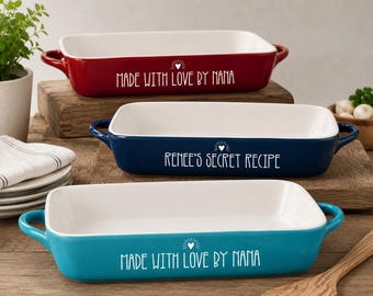 May include: Three rectangular ceramic baking dishes in red, navy blue, and teal. Each dish has a white interior and handles. Text on the dishes reads "MADE WITH LOVE BY NANA" and "Renee's Secret Recipe".