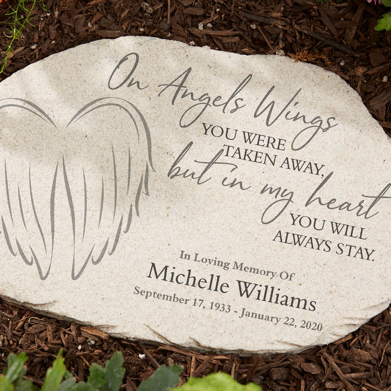 May include: A light gray stone memorial with the inscription "On Angels Wings...but in my heart...You will always stay." Features an angel wing design. Includes the name Michelle Williams and dates September 17, 1933 - January 22, 2020.
