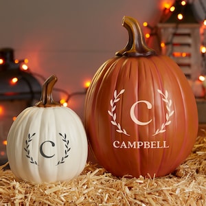 May include: Two decorative pumpkins, one white and one orange, with a wreath and the letter "C" on each. The larger pumpkin has the name "CAMPBELL" written below the letter.