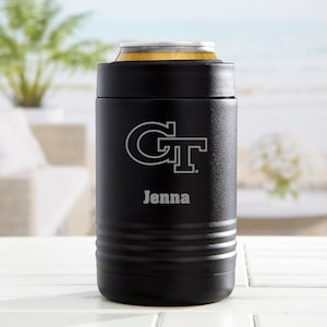 May include: Black can cooler with a silver GT logo and the name "Jenna" engraved. The cooler has a wooden top and a ridged design around the base. The background shows a blurred outdoor scene.