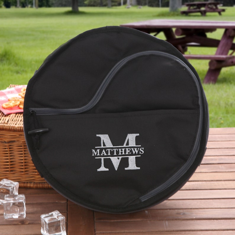 Puede incluir: Bolsa redonda de lona negra con cierre de cremallera y una gran letra "M" bordada con el nombre "MATTHEWS" debajo.
