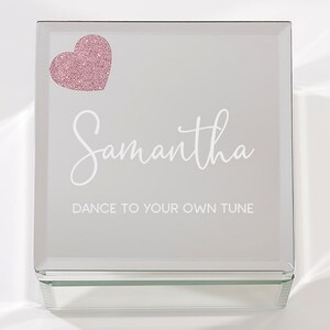 May include: A mirrored glass jewelry box with a pink glitter heart and the name Samantha in white script. The box has the inscription "Dance to your own tune".