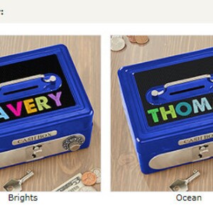 Puede incluir: Dos cajas de metal azules con los nombres "AVERY" y "THOMAS" en letras coloridas. Cada caja tiene una ranura para el dinero, un asa y una cerradura de combinaci&oacute;n. El texto "CASH BOX" est&aacute; impreso en la parte delantera de cada caja.
