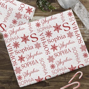 May include: White wrapping paper with a red snowflake and the name "Sophia" repeated in various sizes and styles.
