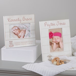 May include: Two white wooden picture frames with a whitewashed wood background. The top frame has the name "Kennedy Grace" and the date "Thursday, November 19, 2023" with the baby's weight and length. The bottom frame has the name "Peyton Jones" and the date "Friday, December 31, 2023". Both frames have a baby photo inside.