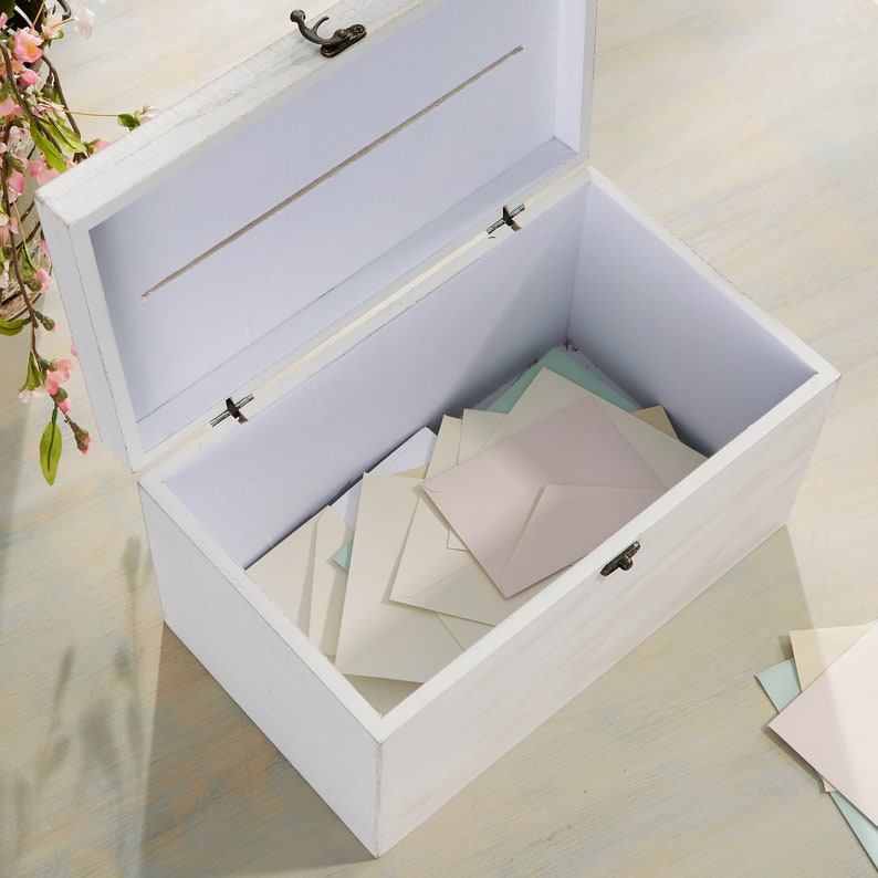 May include: White wooden box with a hinged lid and a slot on the top. The box is open and filled with white and light blue envelopes.