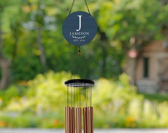 May include: A blue wooden sign with the letter "J" and the text "JAMESON EST. 2019" hangs from a copper wind chime with multiple tubes.