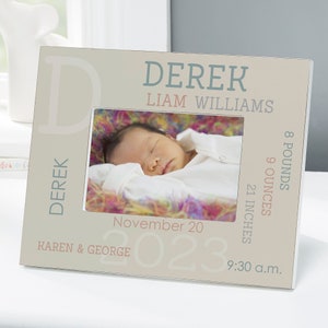 May include: A white picture frame with a beige background. The frame has a photo of a baby sleeping in it. The frame is personalized with the baby's name, Derek Liam Williams, birth date, weight, and length. The text on the frame is in a light blue and pink font.