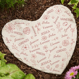 May include: Heart-shaped garden stone with a light beige background. The stone is decorated with the names "Jessica", "Vanessa", "Julie", and "Lorenzo" in a repeating pattern, along with floral illustrations in a muted rose color.
