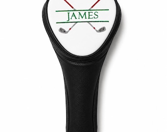 May include: A black golf club head cover with a white top panel. The white panel features an embroidered design of two crossed golf clubs in red and grey, with the name JAMES stitched in green between two horizontal green lines.