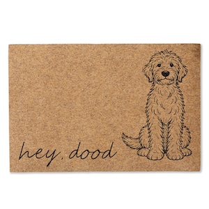 May include: A rectangular tan coir doormat featuring a black line drawing of a curly-haired dog sitting on the right side. The text "hey, dood" is printed in a black cursive script on the lower left side of the mat surface.