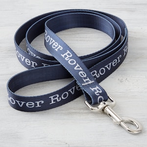 May include: A navy blue dog leash with white text that reads "Rover Rover Rover". The leash has a silver metal clip.