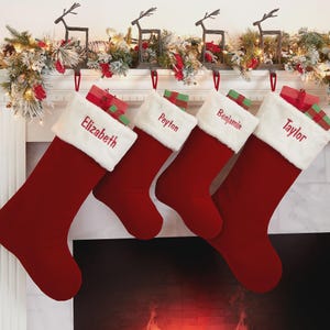 May include: Four deep red Christmas stockings with white faux fur cuffs, each embroidered with a name: Elizabeth, Peyton, Benjamin, and Taylor. Small wrapped gifts are tucked into the top of each stocking, which hang from metal reindeer hooks.