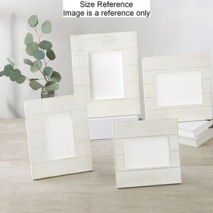 May include: Four white wooden picture frames of different sizes, arranged on a light wood surface. The frames have a distressed white finish and a horizontal plank design.
