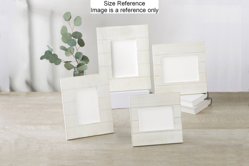 May include: Four white wooden picture frames of different sizes, arranged on a light wood surface. The frames have a distressed white finish and a horizontal plank design.