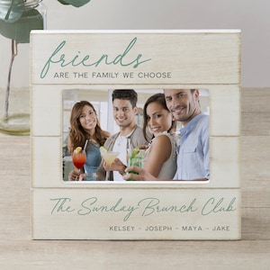 K&ouml;nnte beinhalten: Wei&szlig;er Holzbildrahmen mit einer hellgr&uuml;nen Inschrift, die "friends are the family we choose" lautet. Der Rahmen enth&auml;lt ein Foto von vier Freunden, die Getr&auml;nke halten. Die Inschrift unter dem Foto lautet "The Sunday Brunch Club" mit den Namen "Kelsey - Joseph - Maya - Jake" darunter.