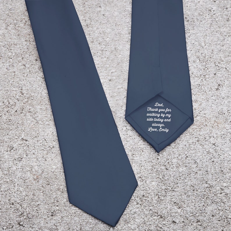 May include: A navy blue tie with a classic design. The tie has a personalized message on the back that reads: "Dad, Thank you for walking by my side today and always. Love, Emily."