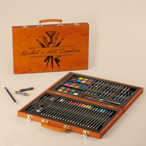 May include: A wooden art supply case with a personalized inscription "Rachel's Art Supplies" and a drawing of art supplies. The case is open to reveal a variety of art supplies, including colored pencils, markers, and paints.
