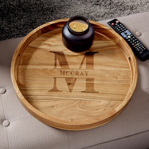 May include: A round wooden serving tray with engraved initials and the name "MCCRAY". A black candle sits on the tray, and a remote control is next to it. The tray is approximately 16 inches in diameter.