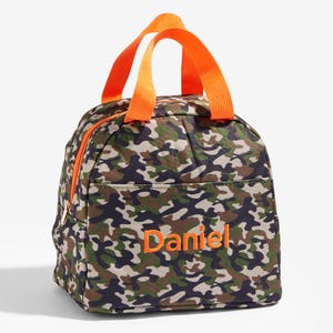 May include: A camouflage-patterned lunch bag with an orange zipper and handles. The name "Daniel" is embroidered in orange on the front. The bag has a front pocket and a zippered closure.