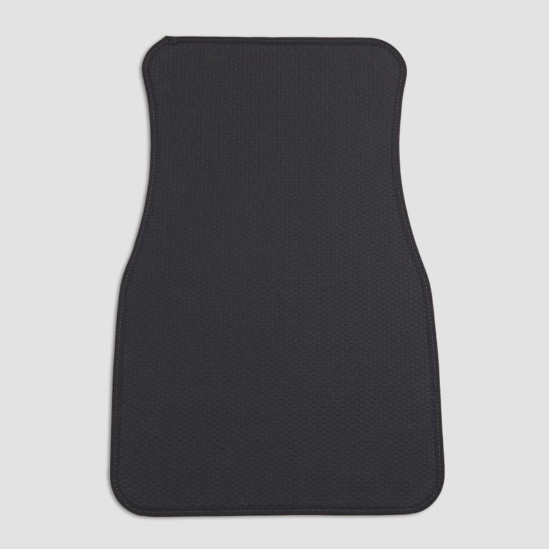 May include: Black car floor mat with a textured surface.
