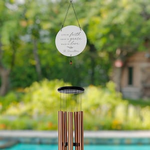 May include: A copper wind chime with a white circular sign that reads "Live by faith, grow in grace, walk in love. The Hamiltons".