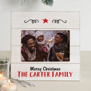 May include: White wooden picture frame with a red star and the text "Merry Christmas THE CARTER FAMILY". The frame has a photo of a family of three.