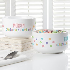 May include: Two white ceramic cereal bowls with colorful donut designs. One bowl says "I Cerealsly Love You!" with the name "Morgan" above it. The other bowl says "I Cerealsly Love You!" with the name "Bray" above it.