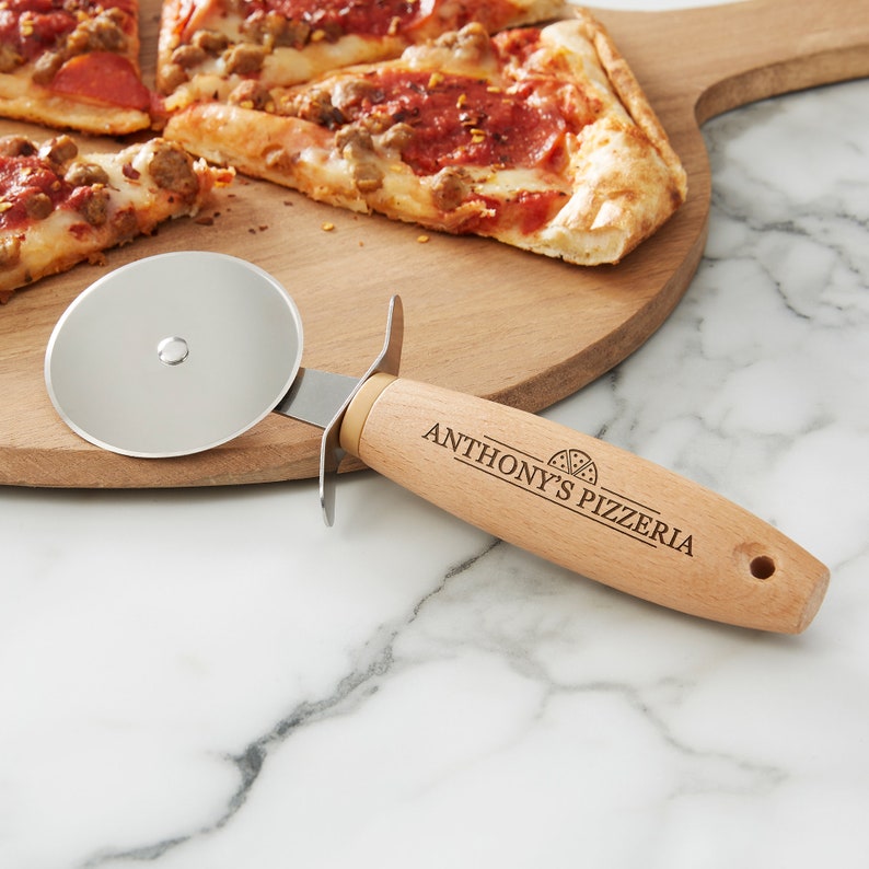 Peut inclure: Un coupe-pizza en bois avec une lame en acier inoxydable. Le manche est grav&eacute; avec "Anthony's Pizzeria" et une petite ic&ocirc;ne de pizza.
