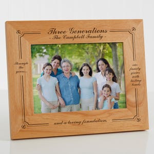 May include: Wooden picture frame with the text "Three Generations - The Campbell Family" and other inscriptions. The frame holds a family photo of seven people. The frame is light brown.