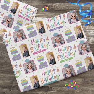 K&ouml;nnte beinhalten: Wei&szlig;es Geschenkpapier mit einem sich wiederholenden Muster aus bunten Geburtstagstorten, Geschenken, Partyh&uuml;ten und Sternen. Das Papier zeigt ein Foto eines jungen M&auml;dchens mit Sonnenbrille und dem Text "Happy Birthday!" mit dem Namen "Eliza", der sich wiederholt.