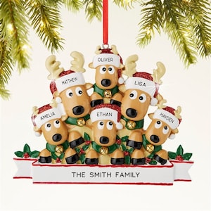 K&ouml;nnte beinhalten: Ein Weihnachtsschmuck mit einer Rentierfamilie. Jedes Rentier tr&auml;gt einen Weihnachtsm&uuml;tze mit einem Namen: Amelia, Matthew, Ethan, Oliver, Lisa und Hayden. Das Ornament hat ein Banner mit der Aufschrift "THE SMITH FAMILY".