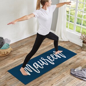 Pu&ograve; includere: Un tappetino da yoga blu navy con il nome "Maureen" stampato in lettere bianche in corsivo. Una persona sta facendo yoga sul tappetino.