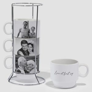 May include: A white mug set with a metal stand. The stacked mugs display black and white photos of couples. A single mug with the text "Love at first sip" is also present.