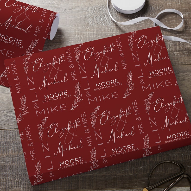 May include: Red wrapping paper with a white repeating pattern of the names Elizabeth and Michael, the date December 3, 2023, and the words "Mr. & Mrs."
