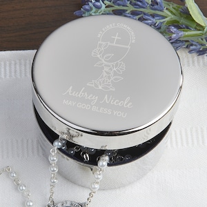 May include: Silver keepsake box with an engraved design of a chalice and cross, the words "My First Communion" and the name "Aubrey Nicole" with the text "May God Bless You".