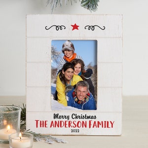 May include: White wooden picture frame with a red star and the text "Merry Christmas THE ANDERSON FAMILY 2022". A photo of a family of four is in the frame.
