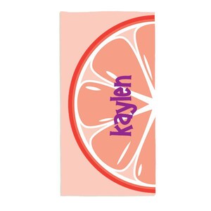 May include: Pink beach towel with a large pink grapefruit slice graphic. The grapefruit slice has a purple text overlay that says "Kaylen".