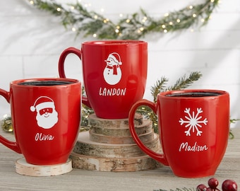 May include: Three red ceramic mugs with white holiday designs. One mug features a Santa face with the name "Olivia", another has a snowman with the name "Landon", and the third has a snowflake with the name "Madison".